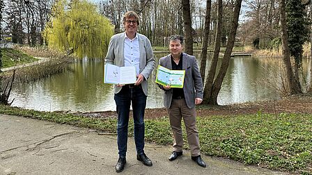 Burgemeester Joppe en Wethouder Delsing met voorleesboeken voor jeugd bij de vijver